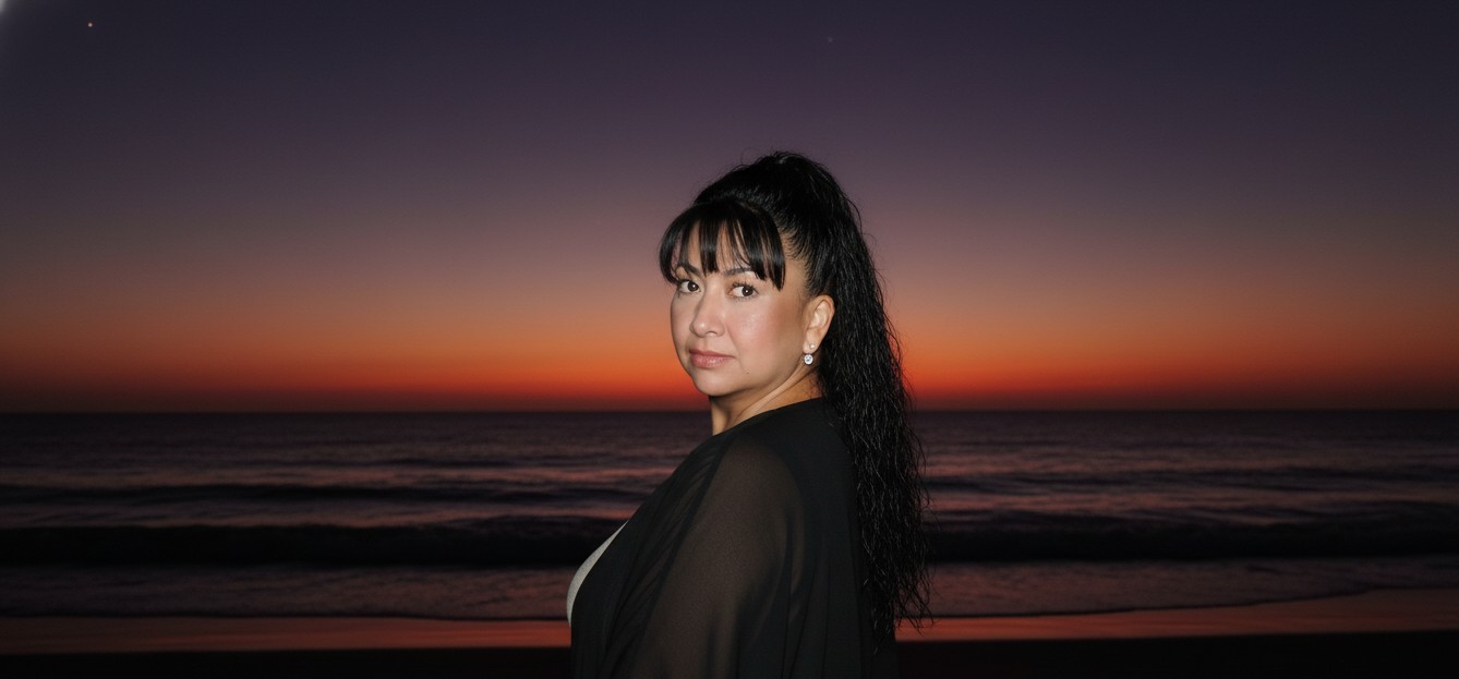 Hazme parecer que estoy en una playa oscura,
pero me sacaron una foto con flash y la cara brilla un poco. Al fondo, añade la puesta de sol, como si el sol se hubiera ocultado en un 98%, dejando un cielo rojo púrpura y casi oscuro. La imagen está tomada desde atrás y me han dicho que me gire para la foto. Llevo un traje negro playero. (Que la cara quede exactamente igual que en la foto).