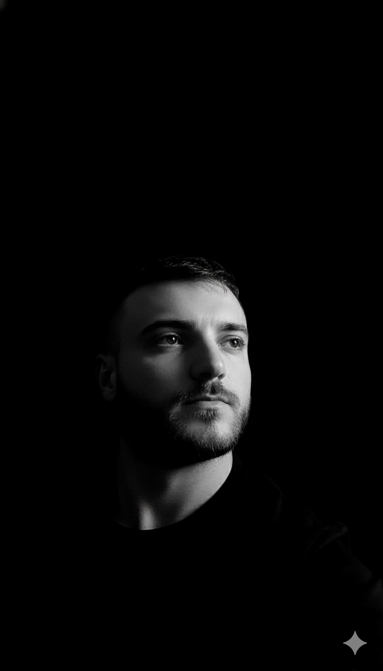 Retrato intenso, hiperrealista y en primer plano en blanco y negro, con iluminación cinematográfica lateral de alto contraste que resalta los rasgos faciales, creando sombras impactantes. El sujeto mantiene una mirada firme y segura hacia arriba, dirigida hacia un vacío oscuro. El entorno irradia misterio, realzado por un fondo minimalista completamente negro. Cada detalle aparece en resolución 4K, preservando fielmente la estructura facial, la textura del cabello y la autenticidad de la fotografía original.