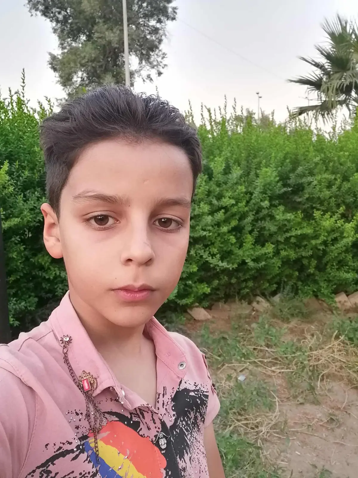 @اللـهم افِعـل بي مـا انت اهلهُ:Hyperrealistic photographic portrait, a person standing beneath a tree, gazing upward with a contemplative, dreamlike expression. Their face and clothing are illuminated by dramatic dappled sunlight and shadows cast by the tree's leaves. The lighting is a surreal mix of deep blue ambient fill and warm, golden hour sunlight, creating a high-contrast and emotional scene.
The subject wears a long- denim button-up shirt, fully buttoned with no other garment underneath. The fabric shows clear interplay of light and shadow with blue shadows and golden highlights across the folds and seams. The tree's branches and leaves frame the subject's face, casting intricate, sharp shadow patterns. All natural skin details are preserved: pores, fine lines, and skin texture.
The background is a vivid blue sky with scattered golden leaves, some captured frozen mid-air as if in a moment of stillness. The entire image has a poetic, cinematic quality.
cinematic still, magical realism, shot on a 50mm f/1.4 lens, wide aperture, shallow depth of field, professional color grading, photorealistic, hyper-detailed, sharp focus on the subject, volumetric lighting, dappled light --v 6.0 --ar 3:4 --style raw